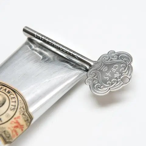 Silver key-shaped bottle opener on a bottle with a label