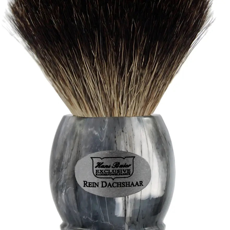 Shaving brush with black and brown bristles and a gray handle on a white background