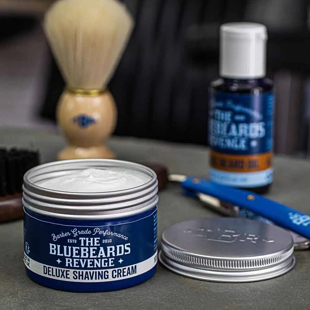 Bluebeards Revenge shaving cream jar with a brush and other products on a gray surface