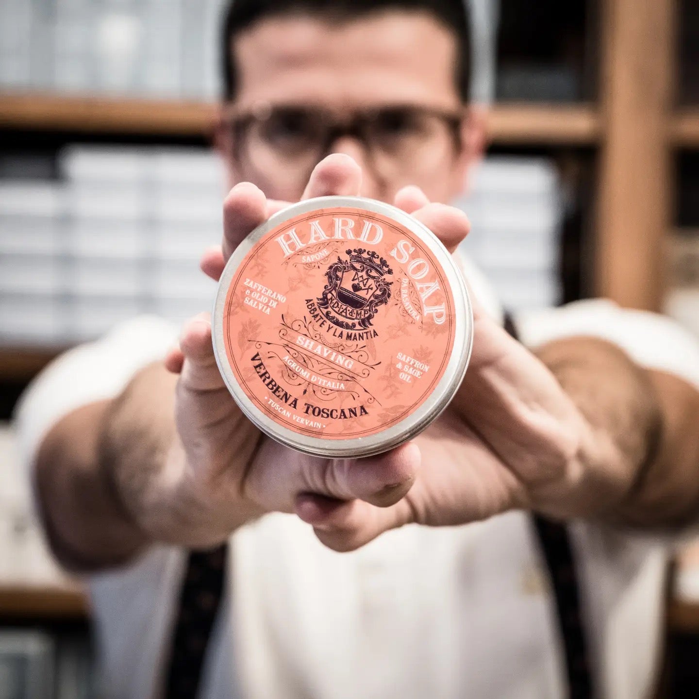 Person holding a container of hard soap with a brand logo.