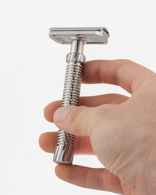 Hand holding a metal shower head with flexible hose on a white background
