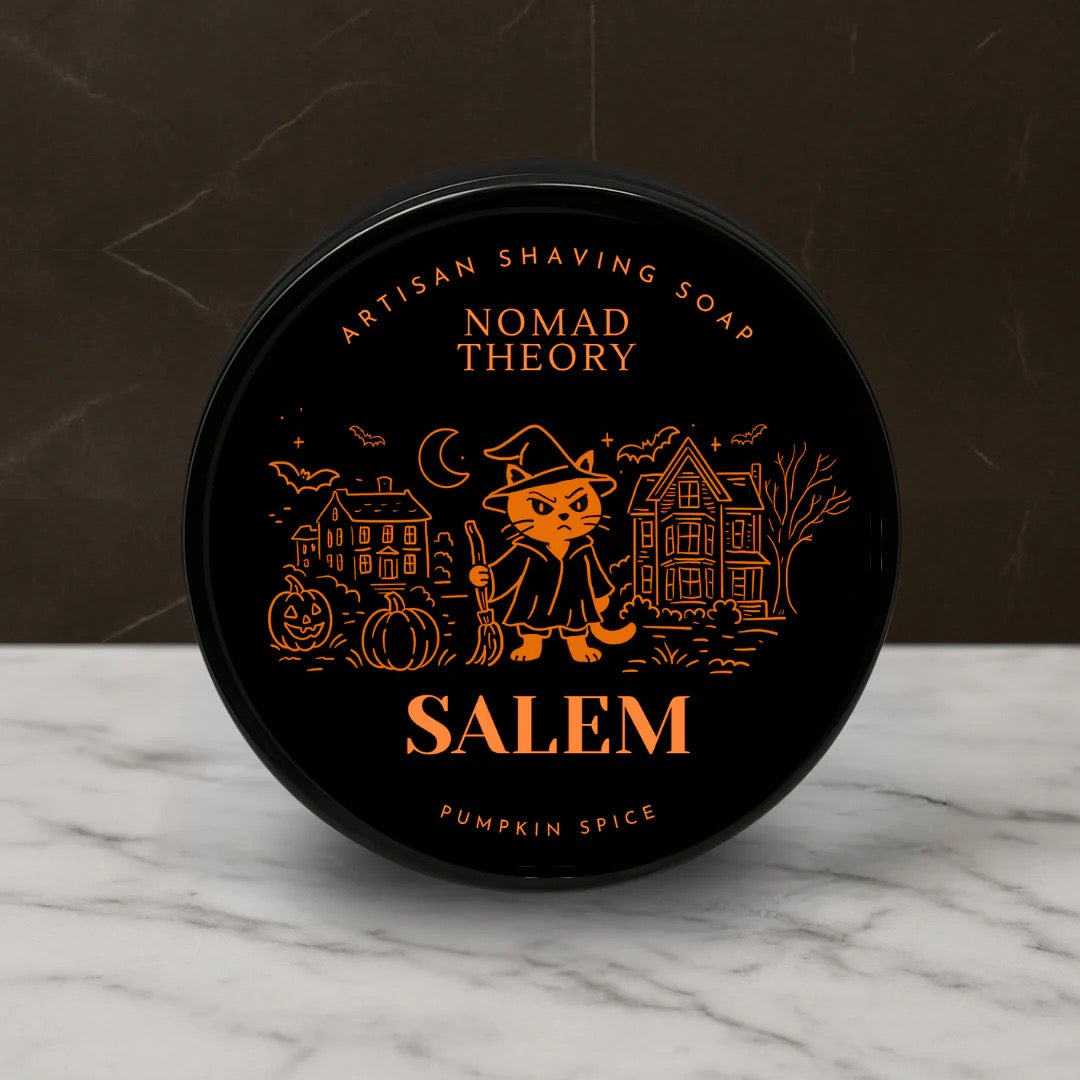 Black container of Nomad Theory Salem Pumpkin Spice shaving soap on a marble surface with a dark background