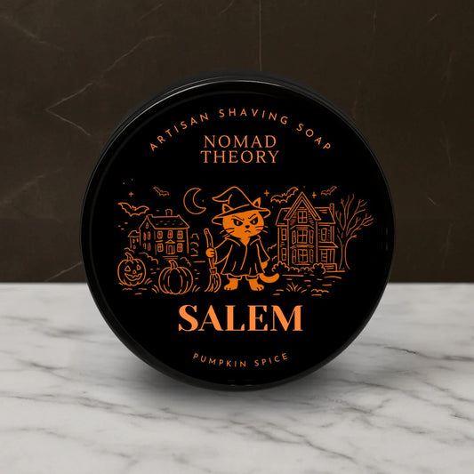 Black container of Nomad Theory Salem Pumpkin Spice shaving soap on a marble surface with a dark background