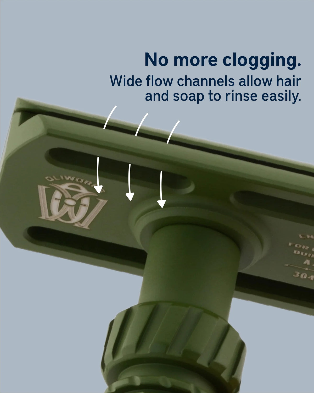 Close-up of an olive green shower head showing the drain opening with white arrows and text reading 'No more clogging. Wide flow channels allow hair and soap to rinse easily.