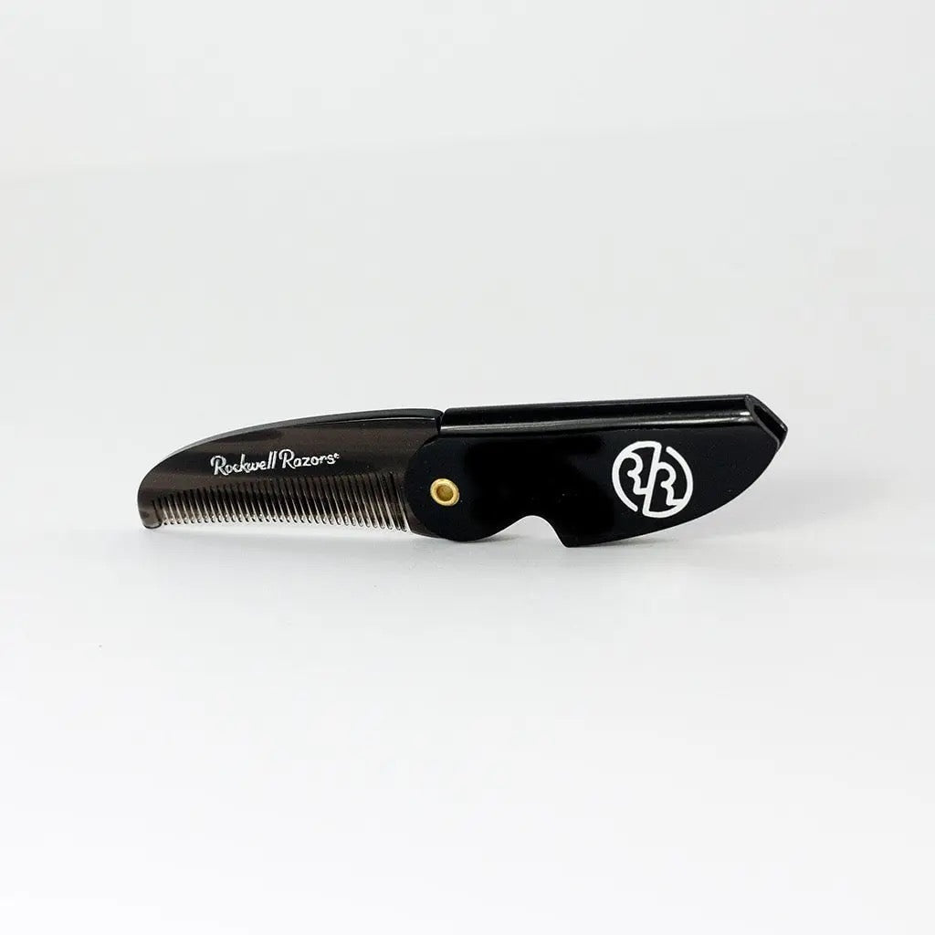 Black comb with gold button on a white background