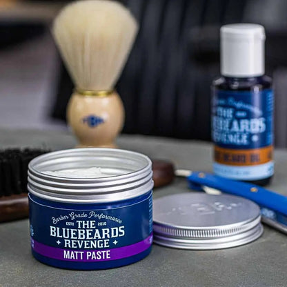 Bluebeards Revenge Matt Paste jar with shaving brush and other products on a gray surface